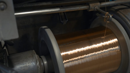 Rotating coils with metal wires at factory. Creative. Winding of metal fiber on bobbins at...