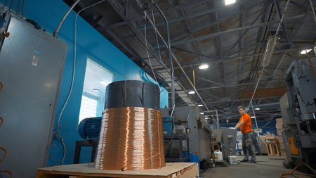 Worker starts machine with copper wire. Creative. Industrial cylinder with winding copper wire....
