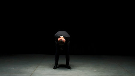 Man in suit stands emotionally on stage. Stock footage. Man in suit stands on stage with dramatic look. Elegant dramatic man on dark stage in emotional productionの写真素材