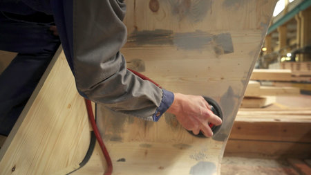 A skilled craftsman is expertly sanding a wooden surface in a well equipped workshop setting. Stock...