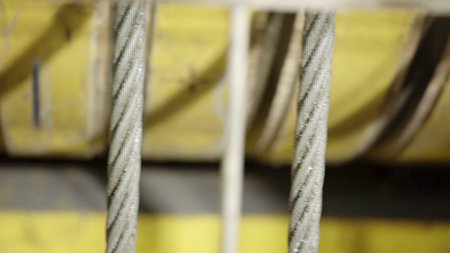 A captivating industrial closeup featuring a steel cable along with various machinery elements....