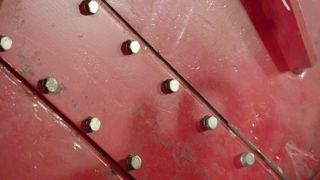 A Close-Up Detailed View of an Industrial Red Metal Plate Featuring Bolts and Nuts. Stock Clipの写真素材