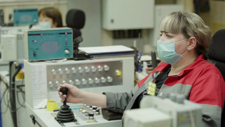 An industrial worker operating a control panel while wearing a protective mask for safety. Stock Clipの写真素材
