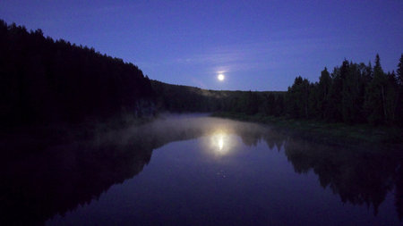 A Serene Moonlit Reflection Over a Tranquil River on a Peaceful Eveningの写真素材