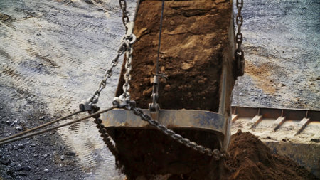 An Excavator Bucket is Lifting a Load of Various Soils on a Busy Construction Site. Stock Clipの写真素材