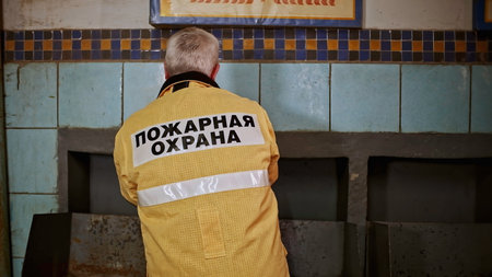 Mature professional fireman getting dressed. Clip. Man wearing protective uniform for the emergency call.の写真素材