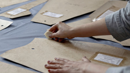 Tailor hands passing around pattern by soap on piece of cloth. Media. Details of clothing atelier.の写真素材