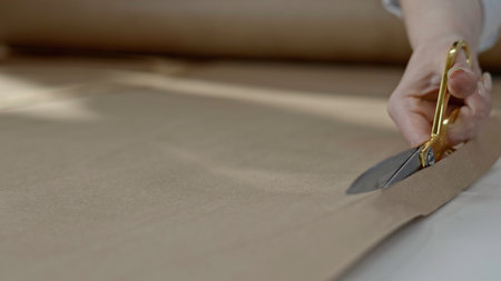 Hand holding big scissors and making cut of tissue. Media. Close up of tailor, designer, stylist or dressmaker making clothes in her studio.の写真素材