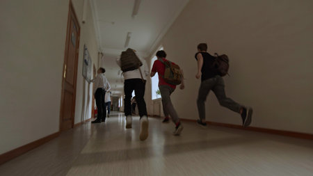 School students in hallway running with backpacks. Stock footage. Smile, fun and knowledge, happy young friends together outside classroom with energy.の写真素材