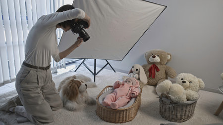 Photosession indoors of a little cute baby in pink warm suit. Cozy interior of the studio with toys.の写真素材