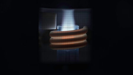 A close up of a stone furnace with a flame inside heating metal spiral. Stock footage. A metal product placed inside to be heated and melted.の写真素材