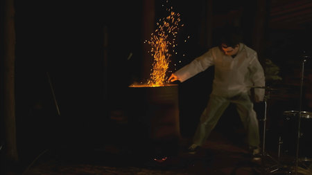 Man with torch in forest at night. Clip. Creepy man with burning torch in dark forest. Ritual torch in hands of frightening man in forestの写真素材