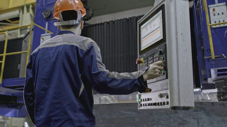 Worker with automated grinding at factory. Stock clip. Worker with remote control of automated...