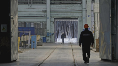 Workers walk in industrial warehouse. Stock clip. Workers in hard hats go to premises at factory. Workers walk around industrial plantの写真素材