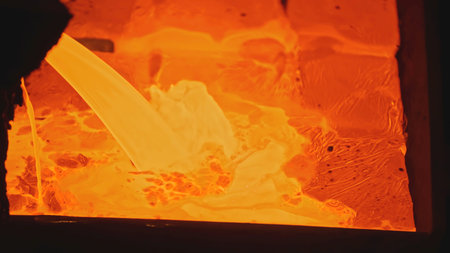 Bright streams of molten metal in factory. Stock footage. Molten metal is poured in streams into molds. Metal alloy fills molds at metallurgical plantの写真素材