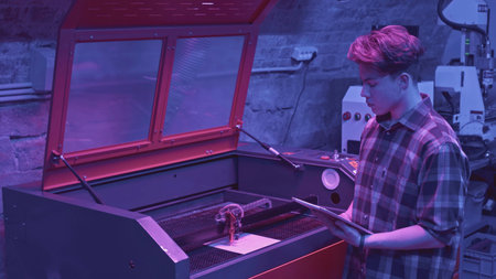 Man watches printing process. Media. Young developer monitors printer operation from tablet. Modern development of robotic printer in laboratoryの写真素材