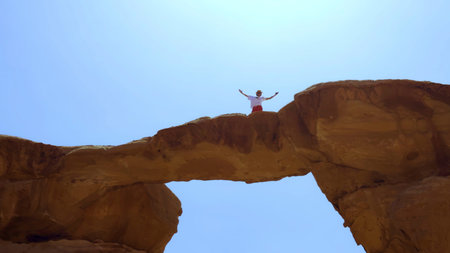 A person enjoying their time on a Rock Arch amidst a vast and beautiful desert landscape. Action