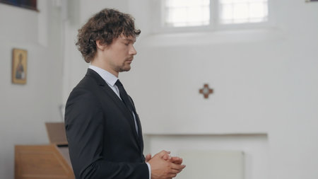 A handsome, worried man. Action. The groom in a suit shifts his hands from nerves.の写真素材