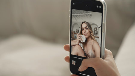 A beautiful woman filming herself on the phone . Action . A young model with wavy white hair who takes a selfie photo on her phone and poses with a special mask.の写真素材