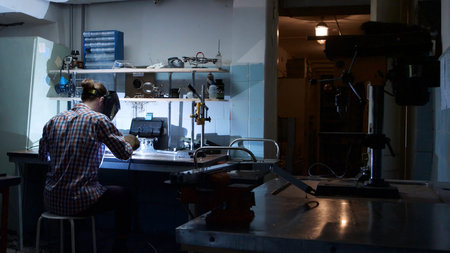 Back view of professional welder man with torch and protective mask welding steel with spark in...