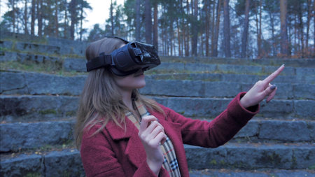 Fair-haired girl outdoor Have fun in VR glasses. Teenager girl enjoying virtual reality glasses...