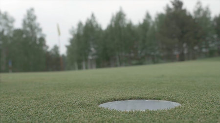 Ball rolling into the hole. Golf ball about to fall into a hole. Golf ball rolling into the hole on...