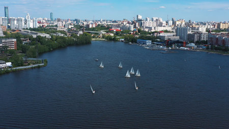 Aerial view of harbor with white beautiful sailing boats in the city pond. Video. Small yachts sailing near the pier on the background of Ekaterinburg city, Russia.の写真素材