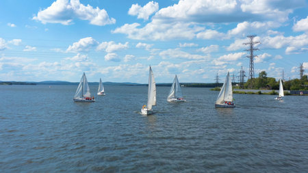 Aerial view of beautiful white yachts sailing in the dark calm water of a river. Video. Small boats...