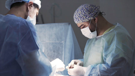 Details of a real surgery in the sterile operating theatre. Action. Medical background of doctors wearing sterile uniform and face mask at work at the hospital.の写真素材