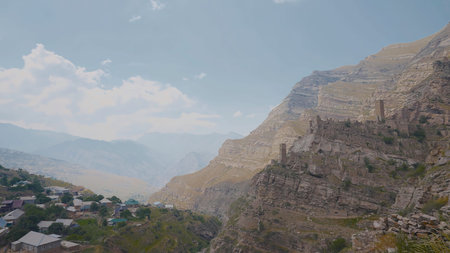 Village near cliff with ruins. Action. Top view of stone city in mountains above residential...