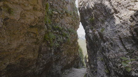 Narrow passage in rocks. Action. Dangerous narrow gorge between two rocks. Narrow passage among mountain rocks with mossの写真素材