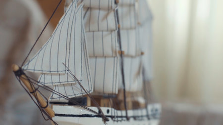 Close-up of the little marine white ship model from the wood on a striped background on the blurred light background. Stock footage. Hobby and collecting conceptの写真素材