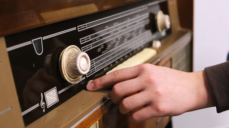 Close-up of mans hand rotating the knob on the old radio. Concept. Vintage technologyの写真素材