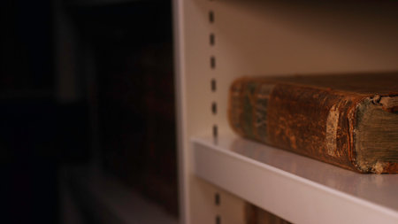 Close-up of hand in white cotton glove taking very old book from the bookshelf in museum or private library. Stock footage. Exploring of the ancient yellowed booksの写真素材