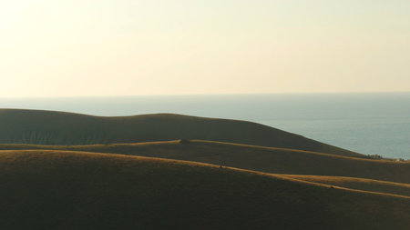 Aerial view of high green hills and blue sea on the background against the evening sky in summer. Shot. Amazing colorful landscapeの写真素材
