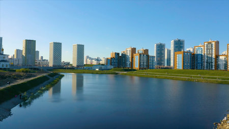 Ekaterinburg, Russia, a pond with a bridge in a new park. Video. Aerial view of a beautiful city district with colorful high rise buildings on blue sky background.の写真素材
