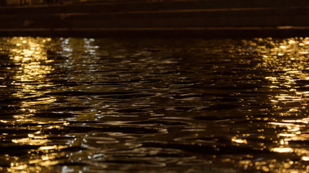 Beautiful night view of a city pond with ripples. Stock footage. Close up of moving water surface with the reflection of lantern lights.の写真素材