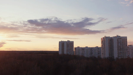 Time lapse effect for amazing clouds and sunset in the sky above the houses. Action. Modern urban architecture, residential high rise buildings located in the sleeping area of the city with autumn trees.の写真素材