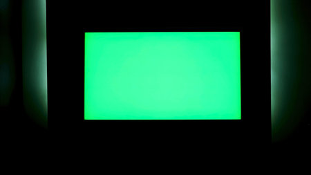 TV with horizontal green screen on a black wall with green illumination. Concept. Close up of chroma...