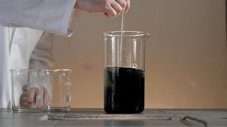 Male researcher carrying out scientific research in a lab. Flasks with liquids in a lab. Liquid in...
