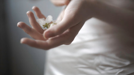 Close up of tender female hands holding white flower buds on blurred background, art concept. Footage. Model with soft flowers lying in her hands.の写真素材