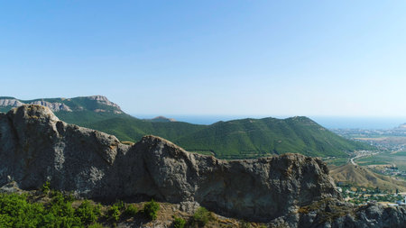 Breathtaking aerial view of the green hill and the valley on blue sky background. Shot. Flying above the small town and green mountains.の写真素材