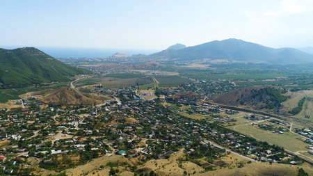 Aerial view of green forested hills and small lake on cloudy sky background. Shot. Flying over summer mountains with growing green trees.の写真素材