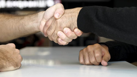 Close up of a table and hands of two men having interview or dialogue. Media. Negotiation concept, business people shaking hands while making agreement.の写真素材