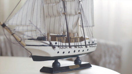 Wooden ship toy model standing on a wooden table in light room, hobby concept. Stock footage. Close...