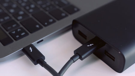 Close up of external hard drive connected to laptop. Action. Black hard disc for backup files and...