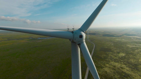 Top view of wind generators. Shot. Drone flies by wings of wind generator. Beautiful flight with wind generators on background of green fields and blue skyの写真素材