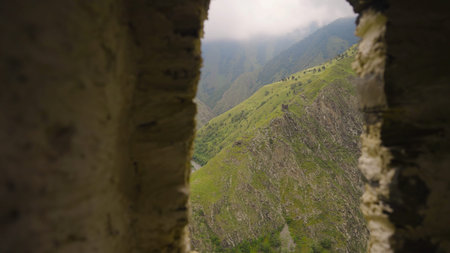 Beautiful view of mountains from window of ruins. Action. Stone arch from ruins with view of green...