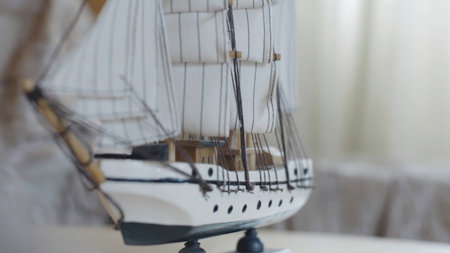 Close-up of the little marine white ship model from the wood on a striped background on the blurred...
