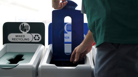 Close up of man putting a noodle box with wooden chopsticks into a paper recycling bin, recycling...
